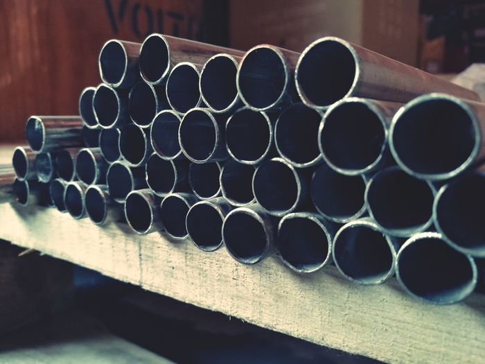 Close-up of metallic pipes on wooden shelf