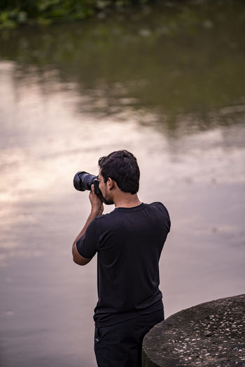 Young india photographer clicking photos near a lake in the morning.