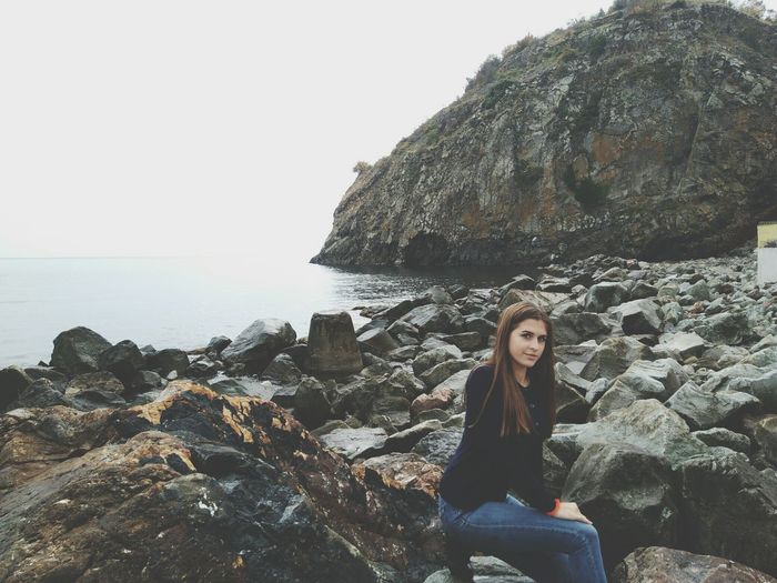 Portrait of woman sitting on rocky shore