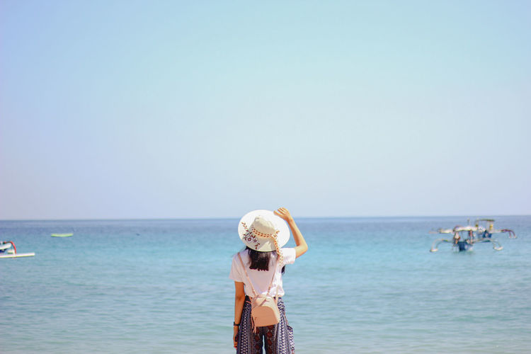 People standing on beach against clear sky