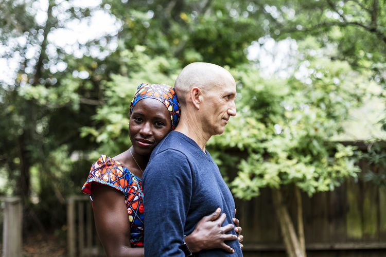 Side view woman wearing african bandana hugging husband by garden