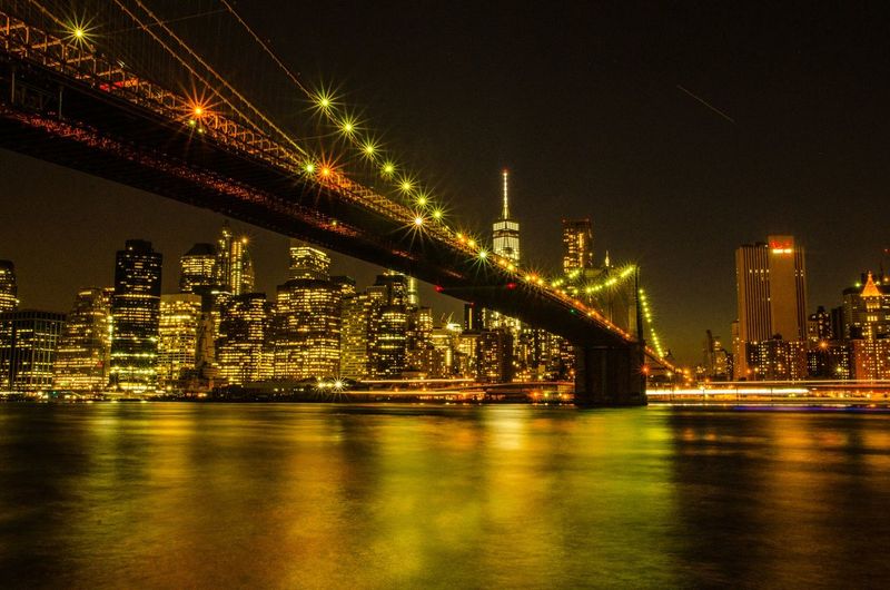 Low angle view of illuminated brooklyn bridge over east river at night