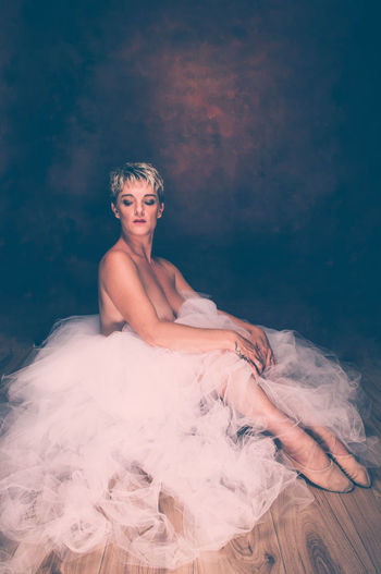 Semi-naked woman wearing tulle tutu against black background