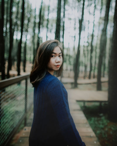 Side view portrait of young woman standing amidst trees