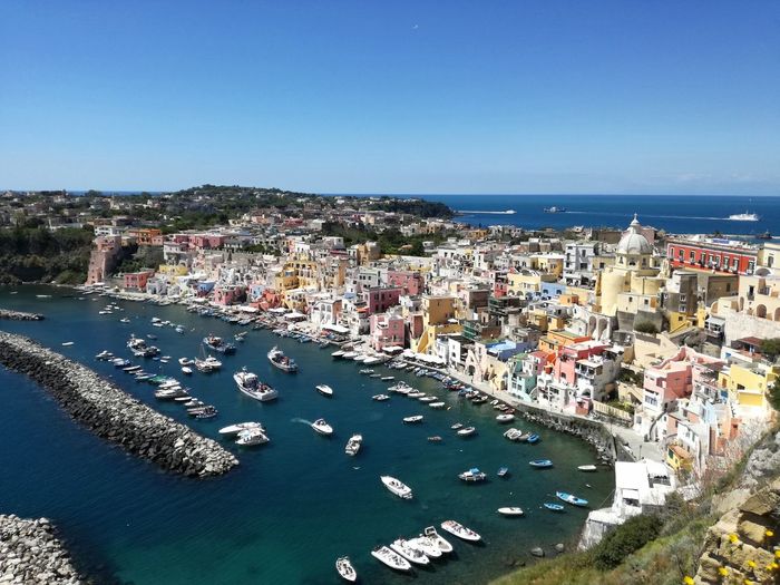 High angle view of town by sea against blue sky