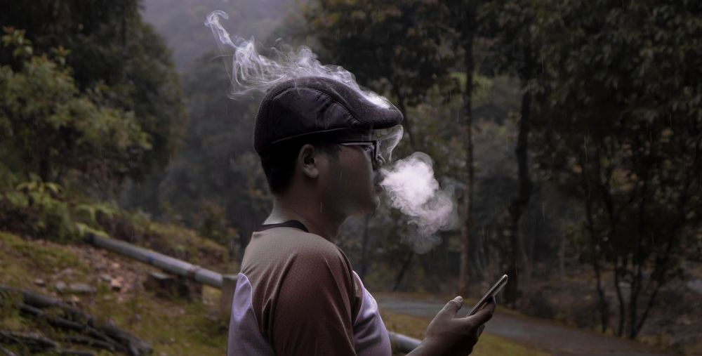 Man exhaling smoke in forest