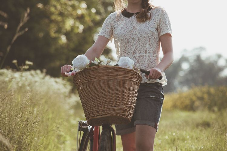 Mid section of a woman with bicycle on landscape