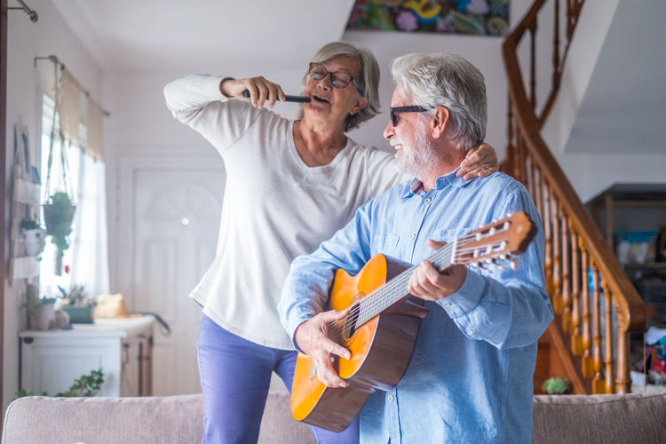 Senior man playing guitar with wife at home
