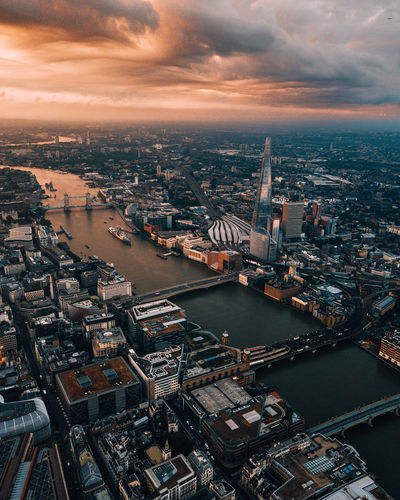 Aerial view of river amidst buildings in city against sky during sunset
