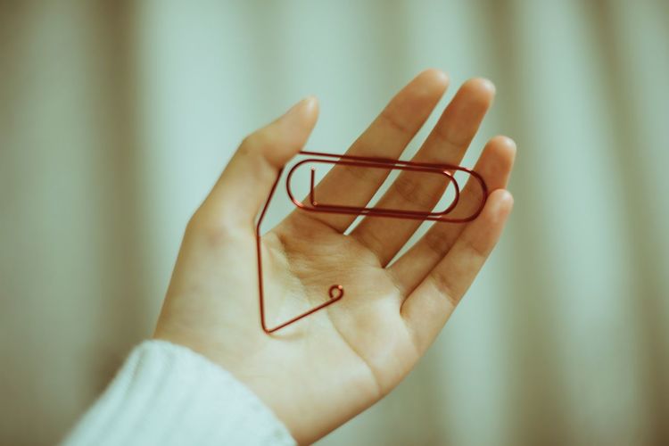Cropped hand of woman holding paper clip