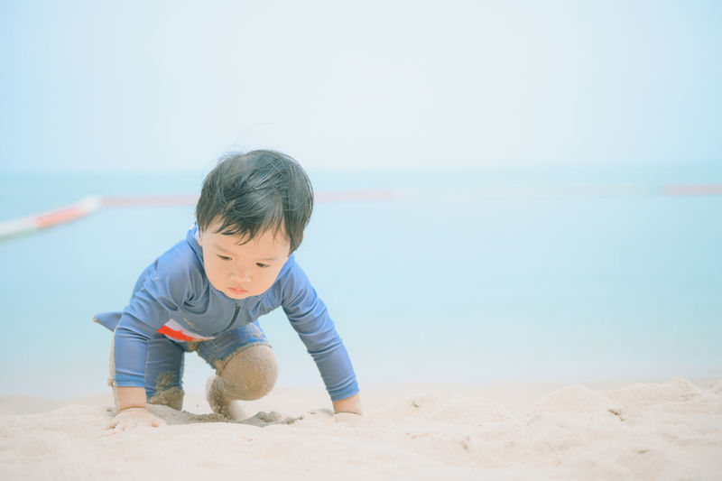 Boy looking at beach against sky