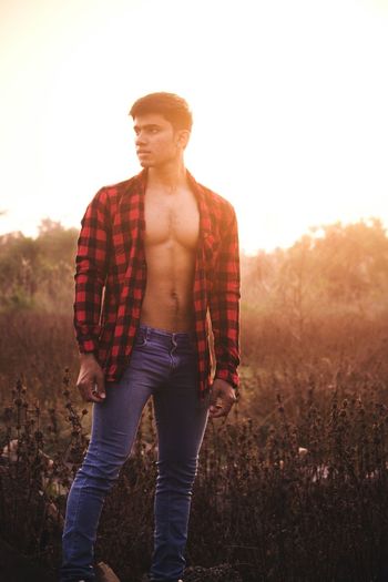Man in fully unbuttoned shirt standing on field