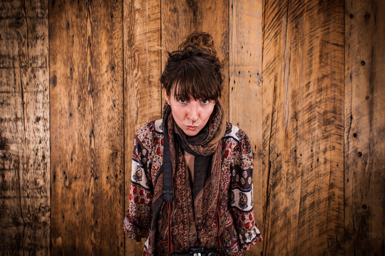 Portrait of woman standing against wooden wall