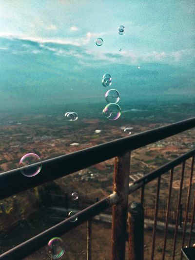 Close-up of bubbles on railing against landscape