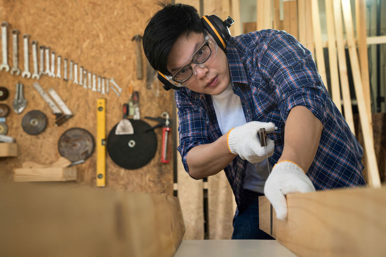Portrait of carpenter cutting wood in workshop