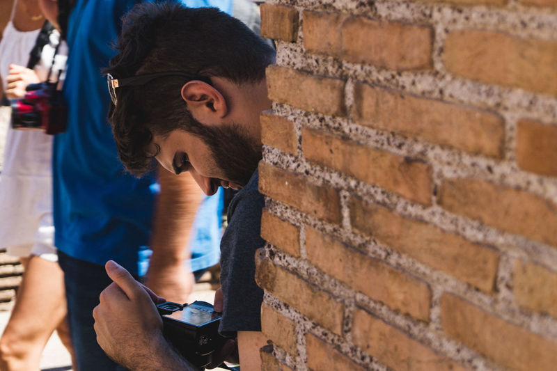 Man holding camera by brick wall