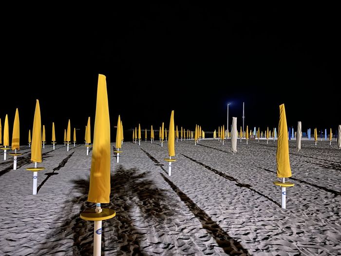 Wooden posts on beach against clear sky at night