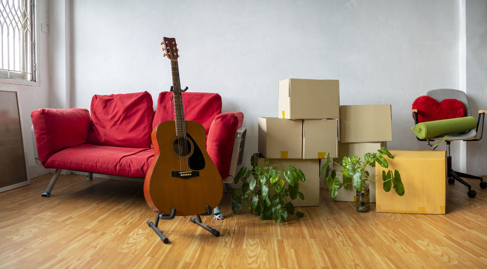 Moving day concept, cardboard carton boxes stack with household belongings in modern house 