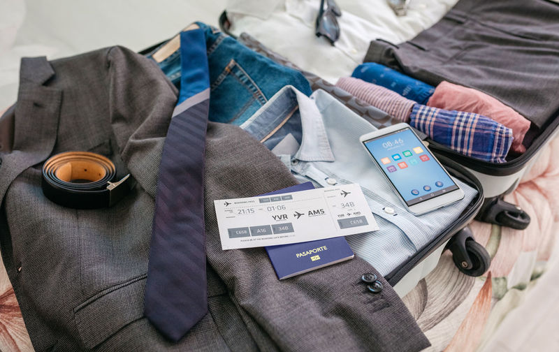 High angle view of mobile phone over clothes in suitcase
