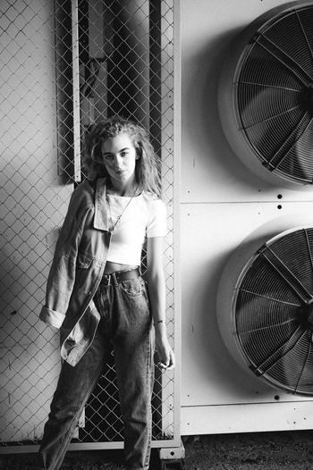 Portrait of teenage girl standing against exhaust fans