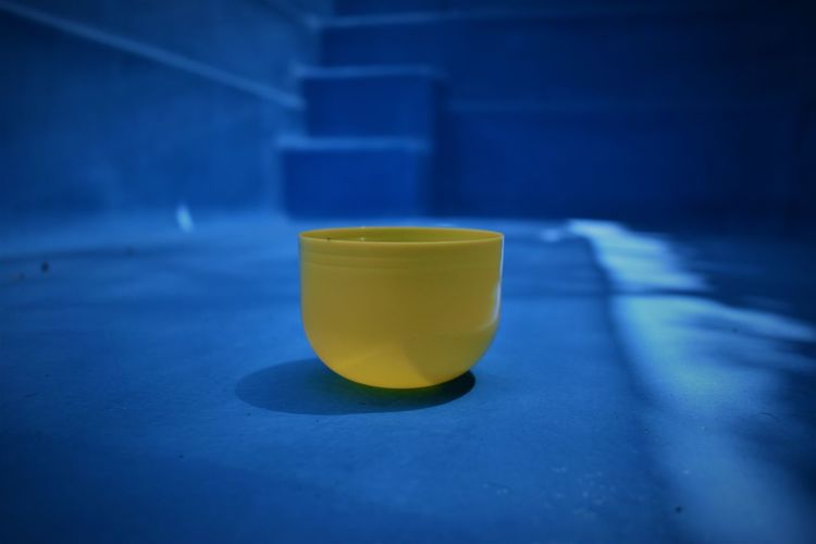 Close-up of yellow plastic container on blue floor