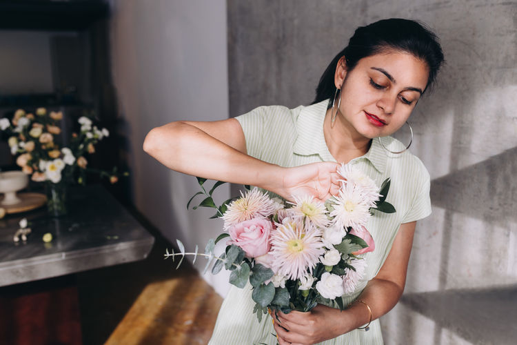 Woman in a light green dress of indian ethnicity making a spring bouquet of flowers