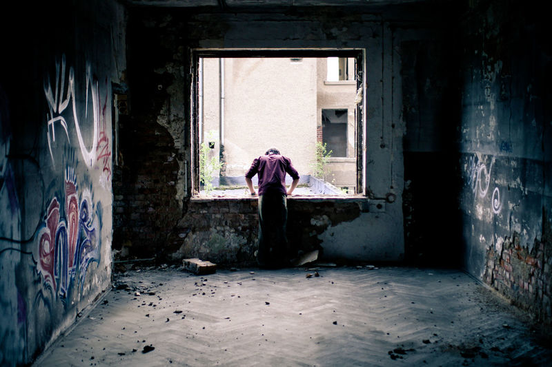 Young man looking out of the window of an old factory in leipzig, germany
