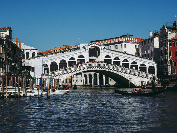 Arch bridge over canal in city against clear sky