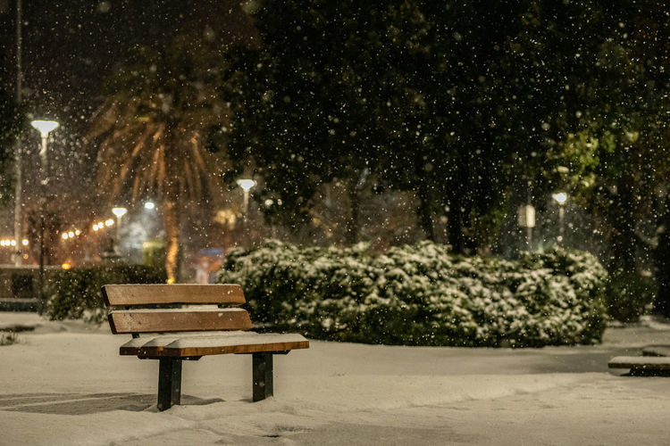 Empty bench in park during winter at night