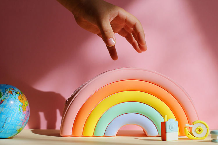 Child hand reaches case in form of rainbow. concept of back to school, diversity, inclusivity