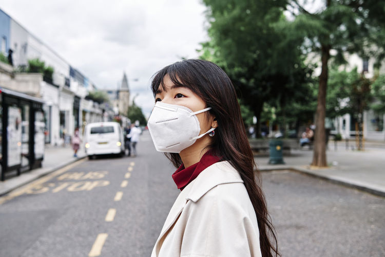 Contemplating woman with protective face mask in city