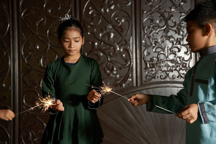 Portrait of malay girl  with traditional clothing playing fireworks sparkler  