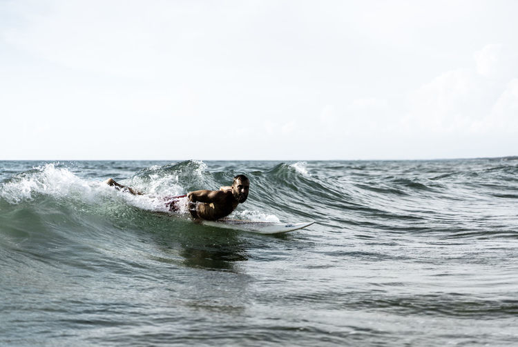 Full length of man lying on surfboard in sea