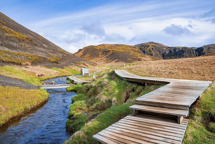 Wooden footpath and changing rooms by hot river stream in reykjadalur valley