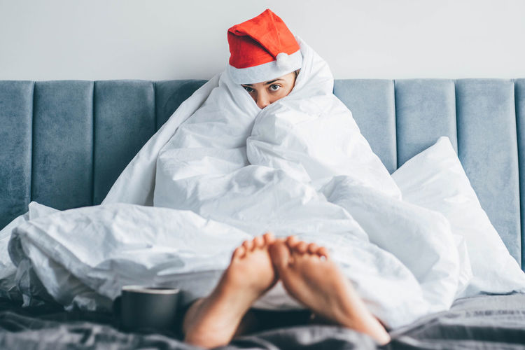 Portrait of woman wrapped in blanket sitting on sofa