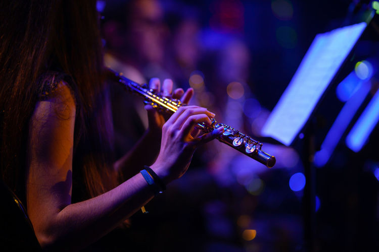 Midsection of woman playing flute in music concert