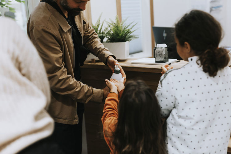 Father squirting hand sanitizer on daughters hands