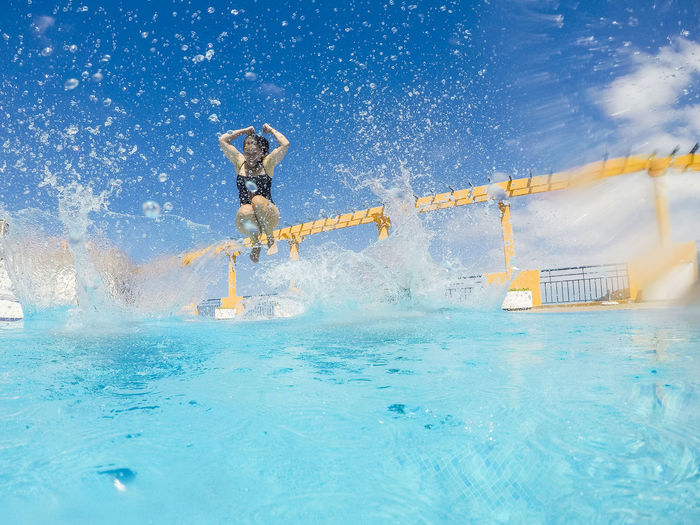Woman diving in swimming pool against sky