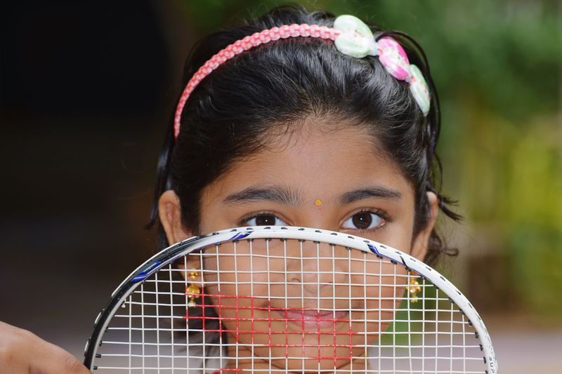 Close-up portrait of girl holding badminton racket