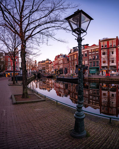 Street by canal against buildings in city at dusk
