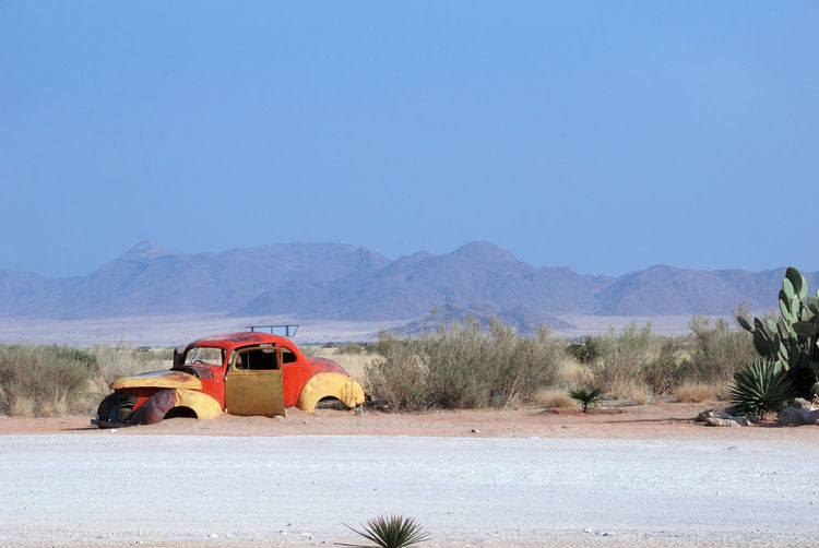 Car on desert against clear sky