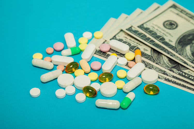 Money pills. medicine pills on dollar bills on a blue background covid-19 coronavirus pills are in