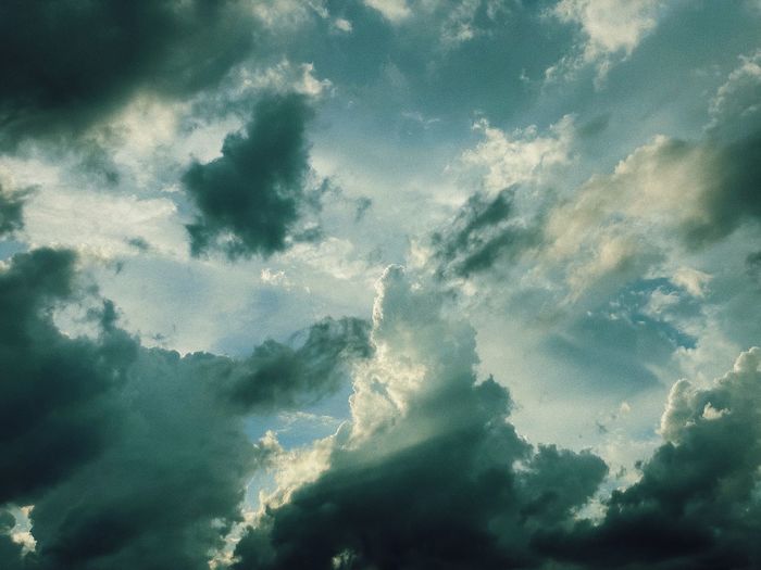 Low angle view of sunlight streaming through clouds