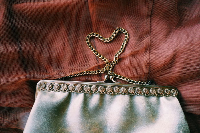Close-up of heart shape made from purse on brown fabric