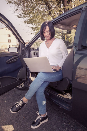 Midsection of mature woman using laptop sitting in car