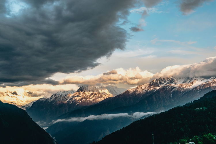 Scenic view of mountains against cloudy sky during sunset