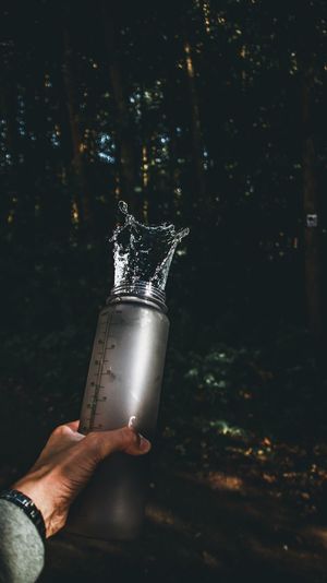 Cropped hand holding water bottle at forest