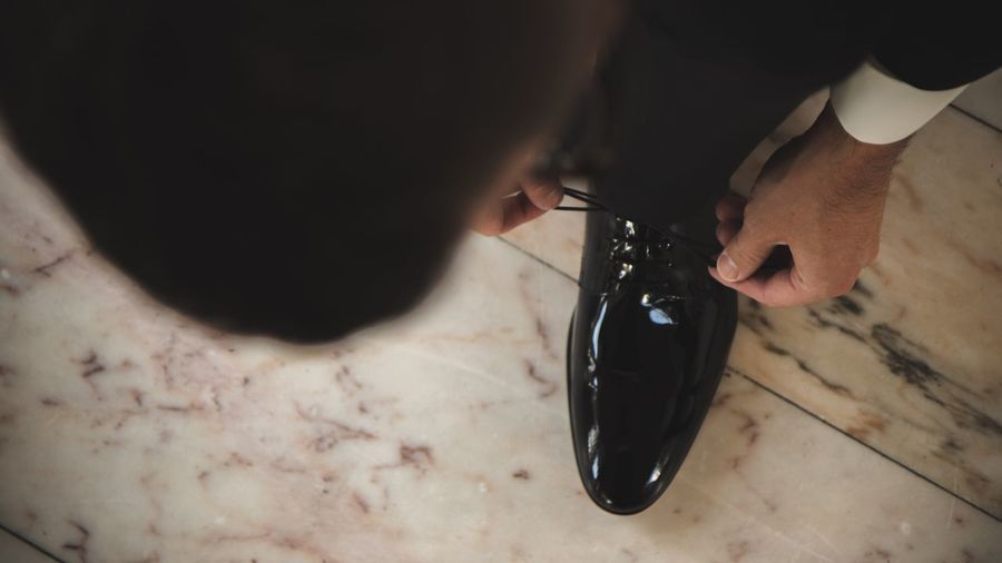 Low section of businessman tying shoelace on marble floor