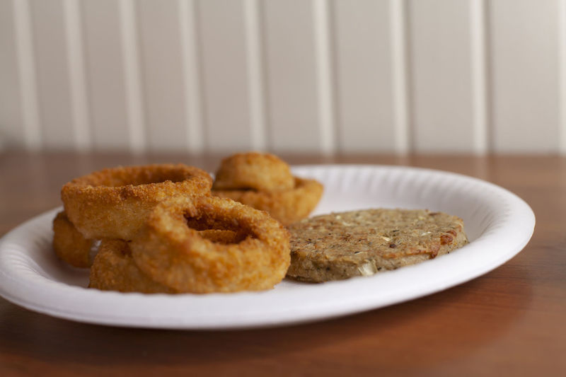 Close up of onion rings and a veggie burger on a plate