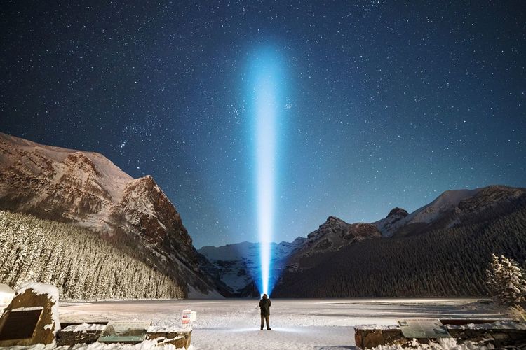 Scenic view of man illuminating sky at night against snow covered landscape